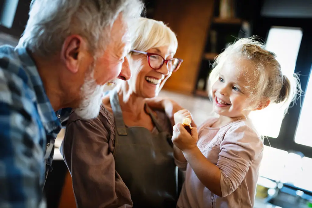 grandparents holding their granddaughter all smiling