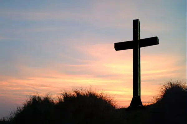 a cross in front of a sunset