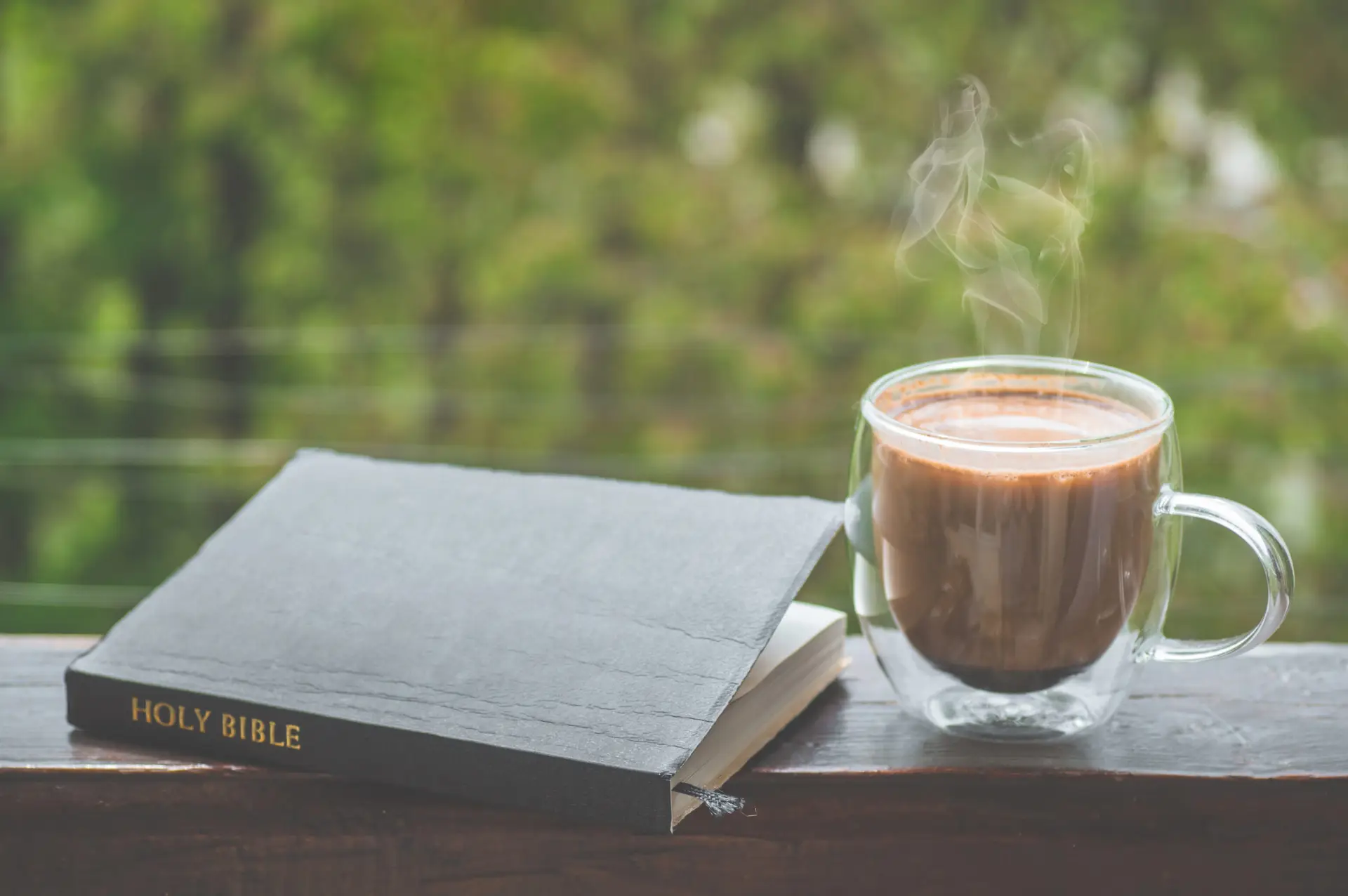 a bible sits in a window sill next to a cup of coffee