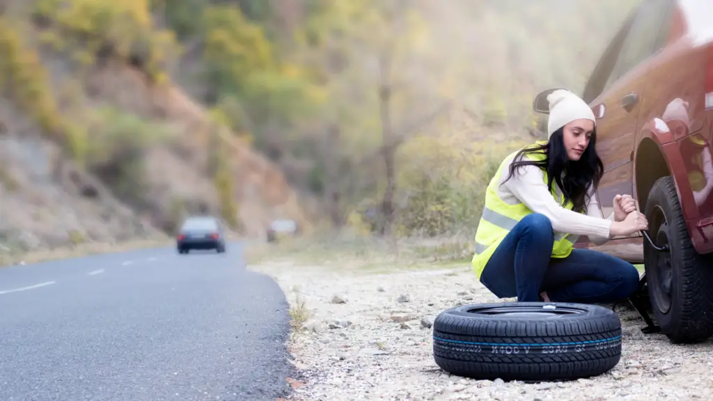 Woman changing a flat tire on the side of the road as part of the professional development skill