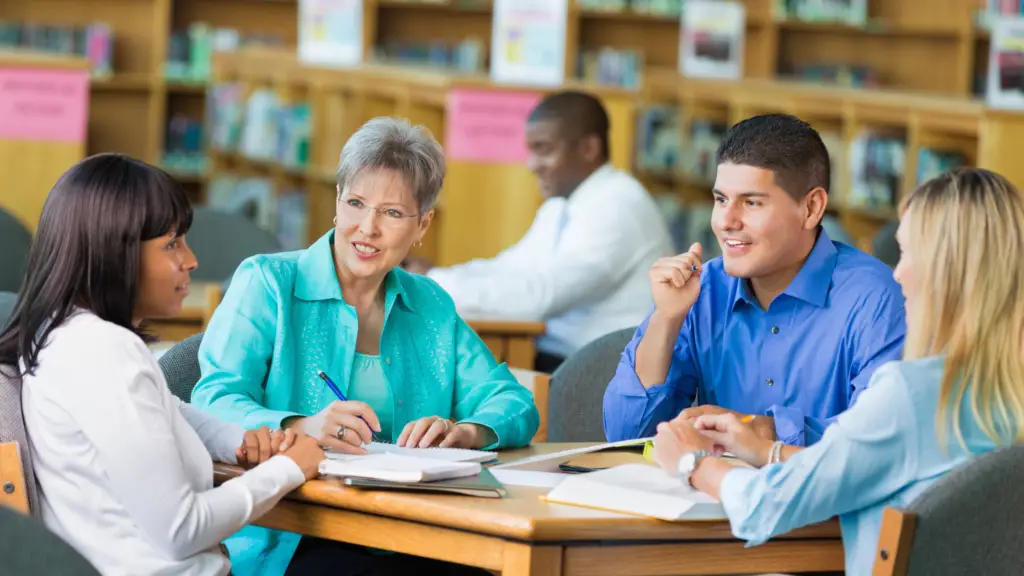 Teachers sitting around a table in a library discussing biblically integrated instruction