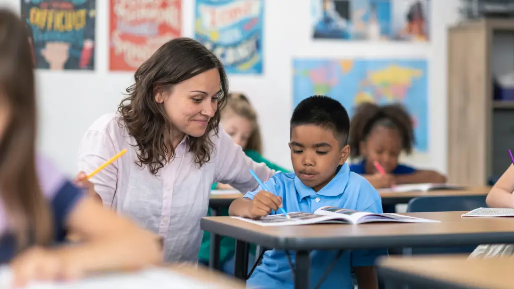 Teacher helping a student at his desk in their classroom