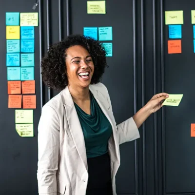 woman smiling as she organizes post it notes on a wall